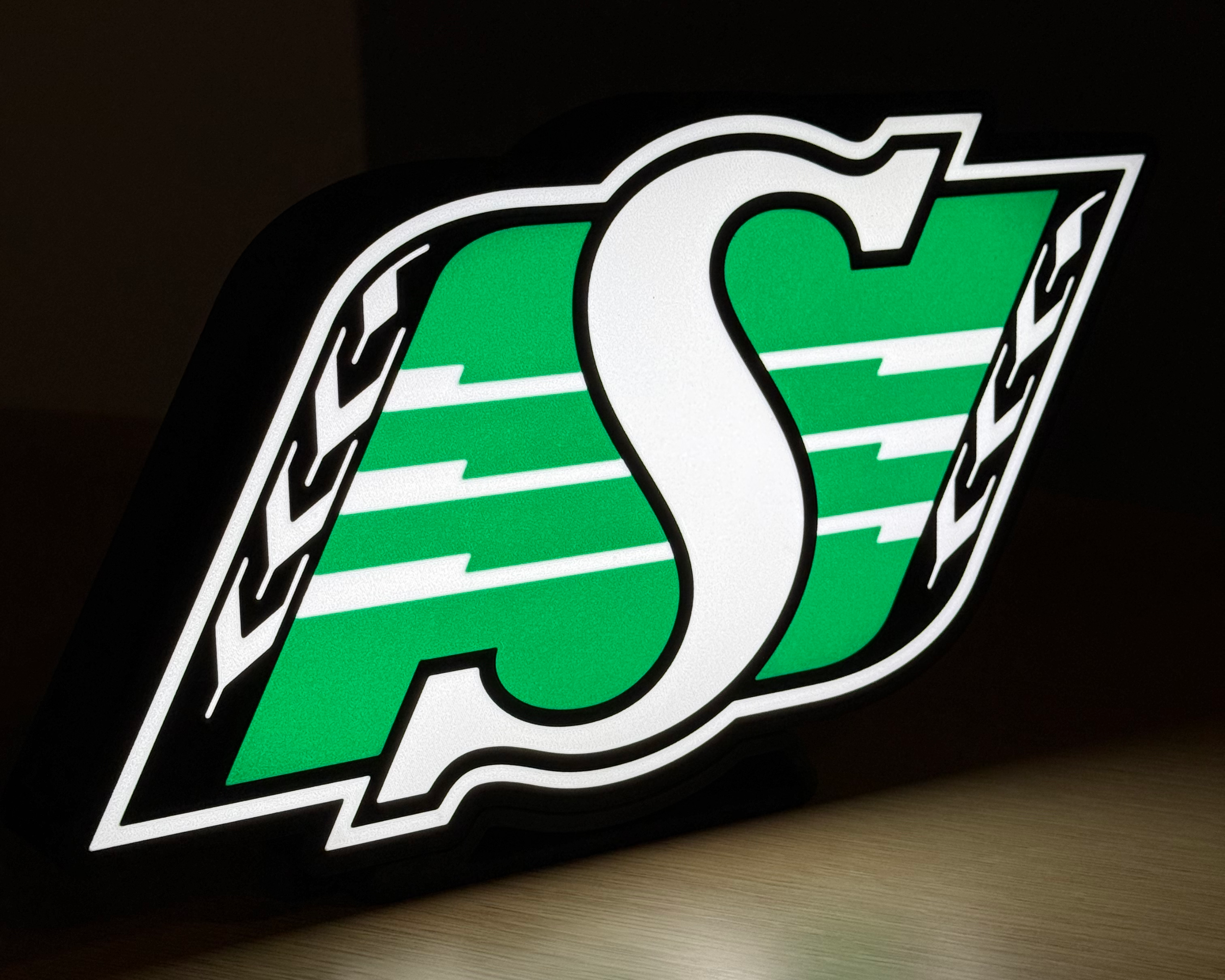Illuminated angled view of the Saskatchewan Roughriders logo lightbox against a dark background