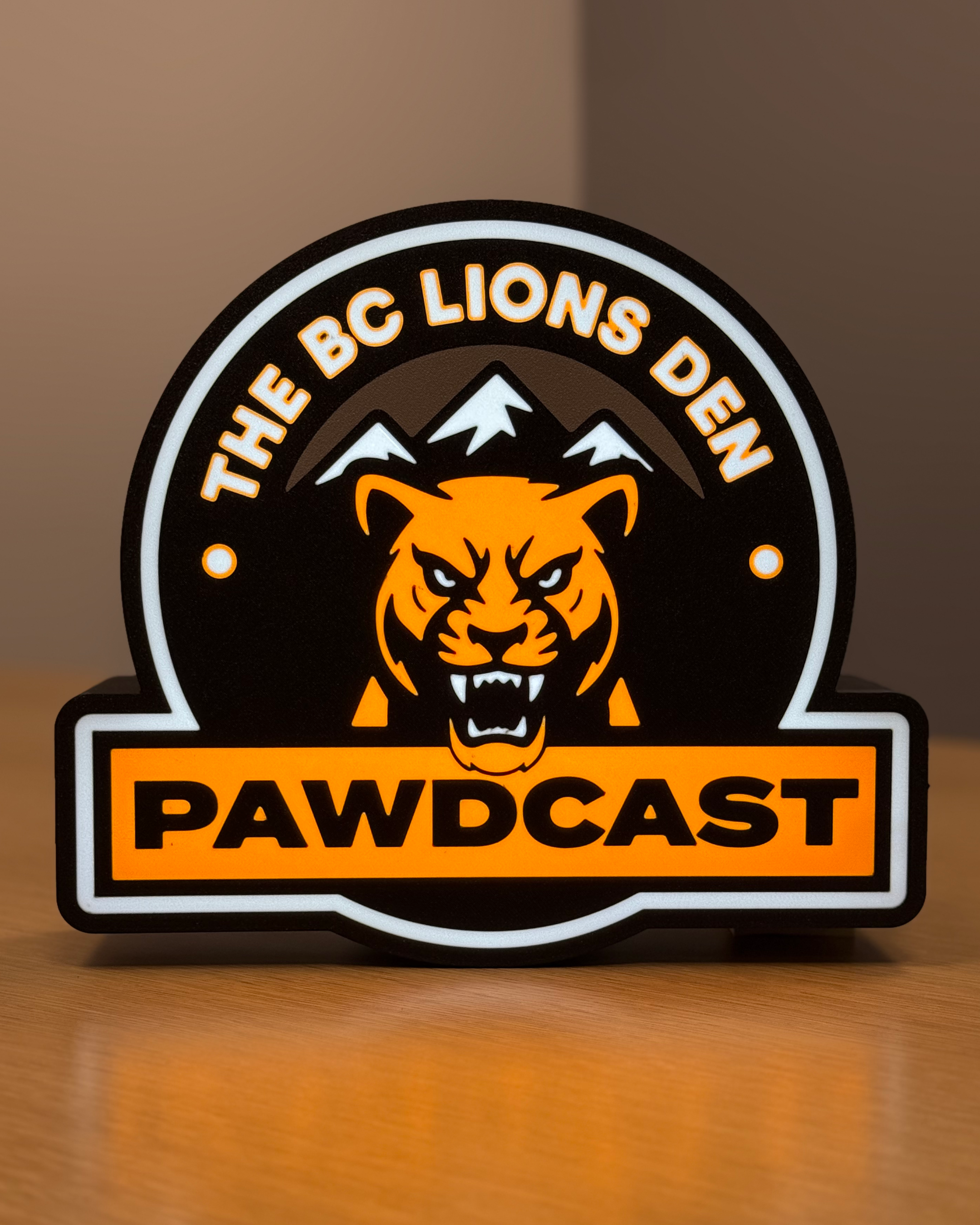 Illuminated front view of the BC Lions Den Pawdcast lightbox with warm ambient lighting