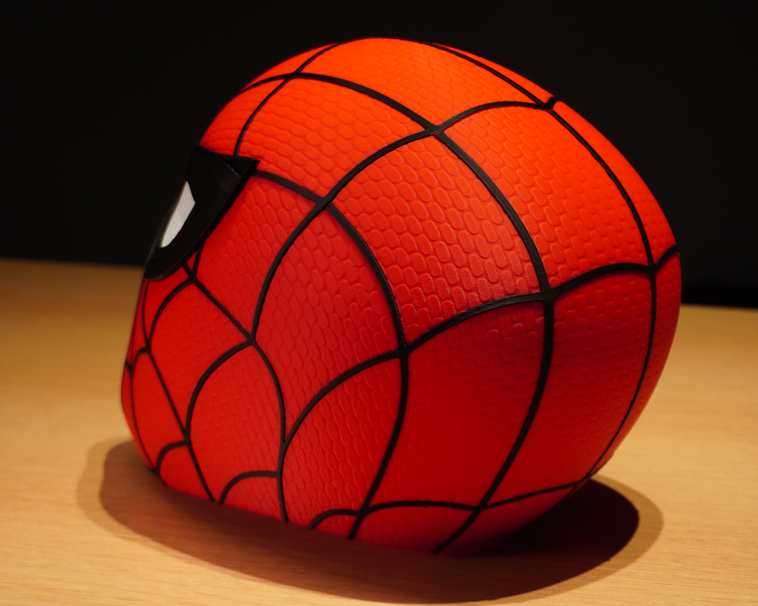Rear three-quarter view of the Spider-Man mask showing the web pattern continuing around the shell