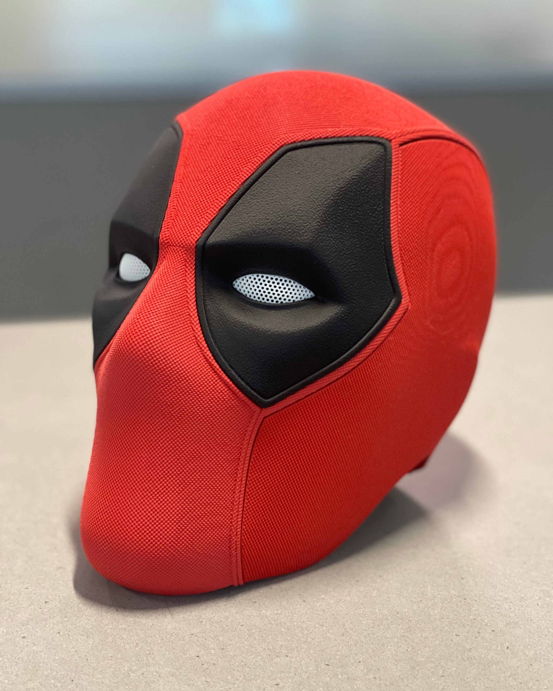 Three-quarter view of the Deadpool mask showing the curved shell, layered eye panels, and textured surface finish