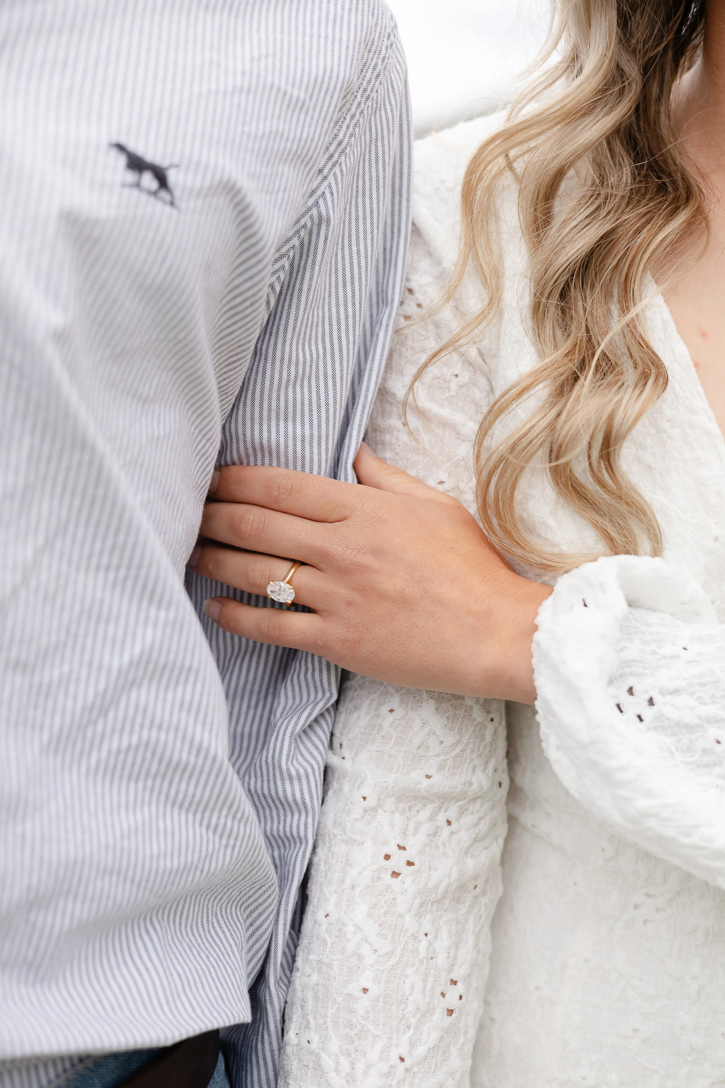 Woman wearing an engagement ring holding her fiancé’s arm during an outdoor couples photography session in Yass