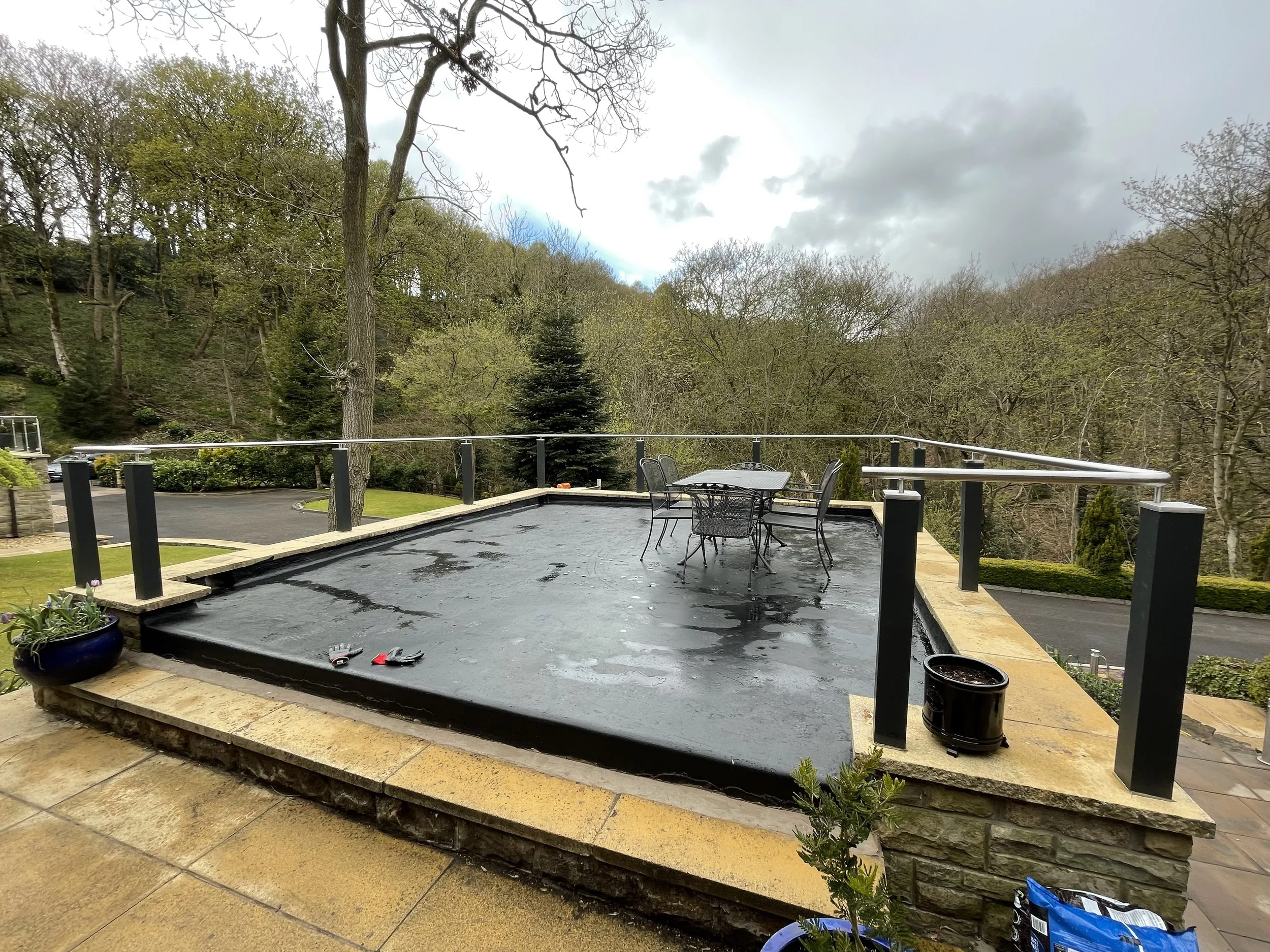 Stainless steel handrail fitted to existing timber posts around a raised garden terrace.