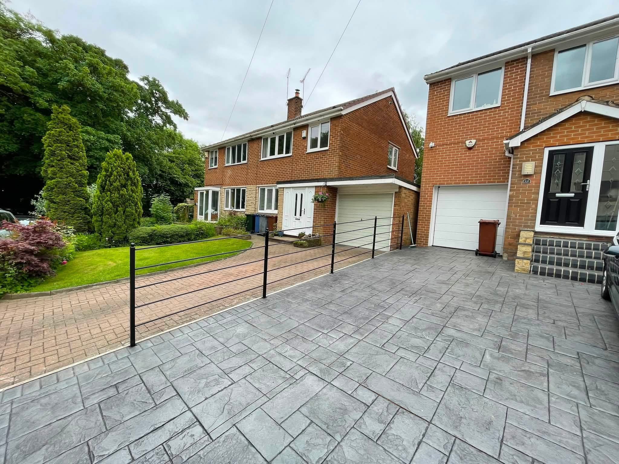 Black steel estate style railings with horizontal bars and decorative post tops, following the slope between neighbouring driveways.