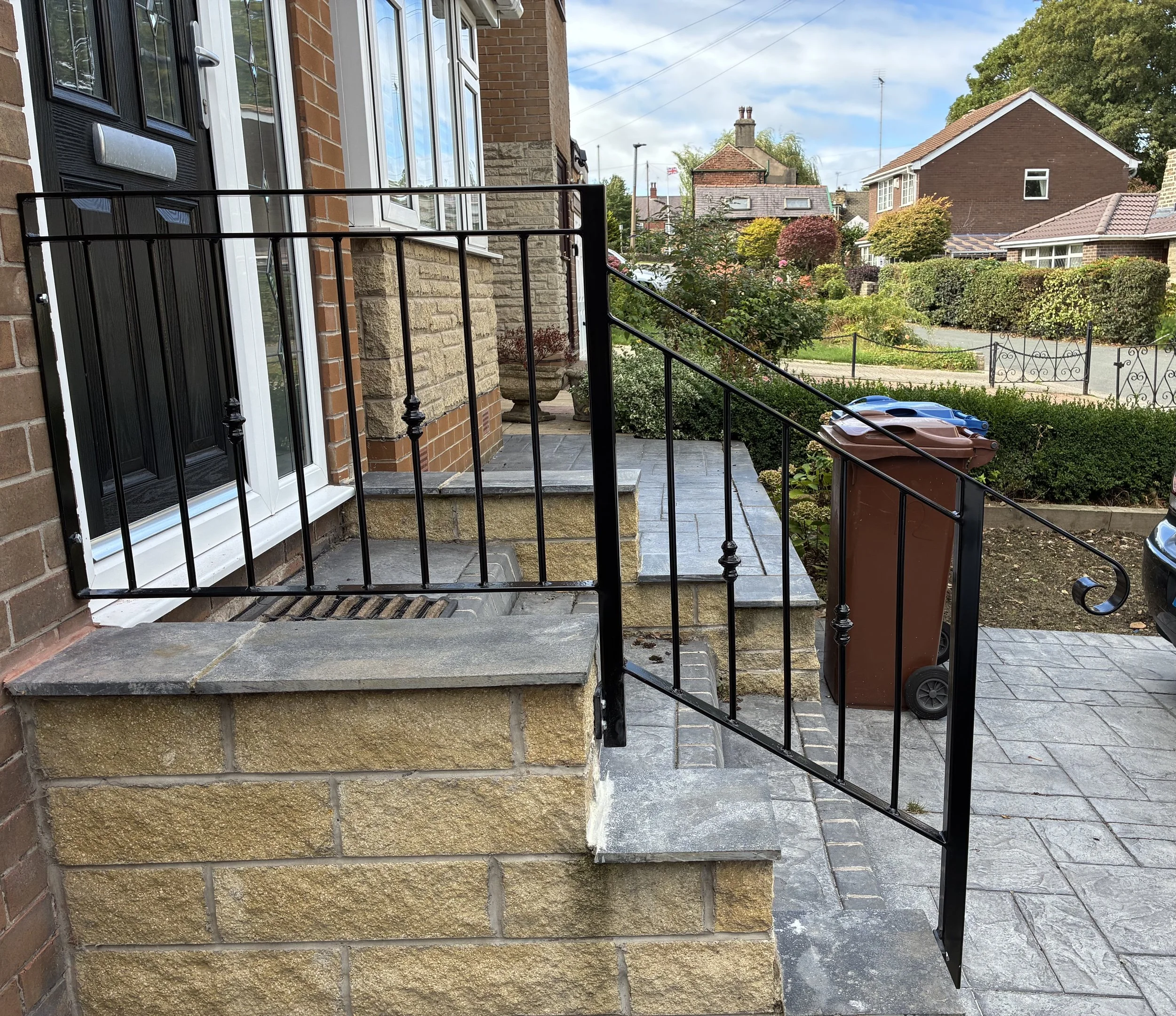 Decorative black steel handrail fitted around the front doorstep and down the stone steps, complementing the character of the property.