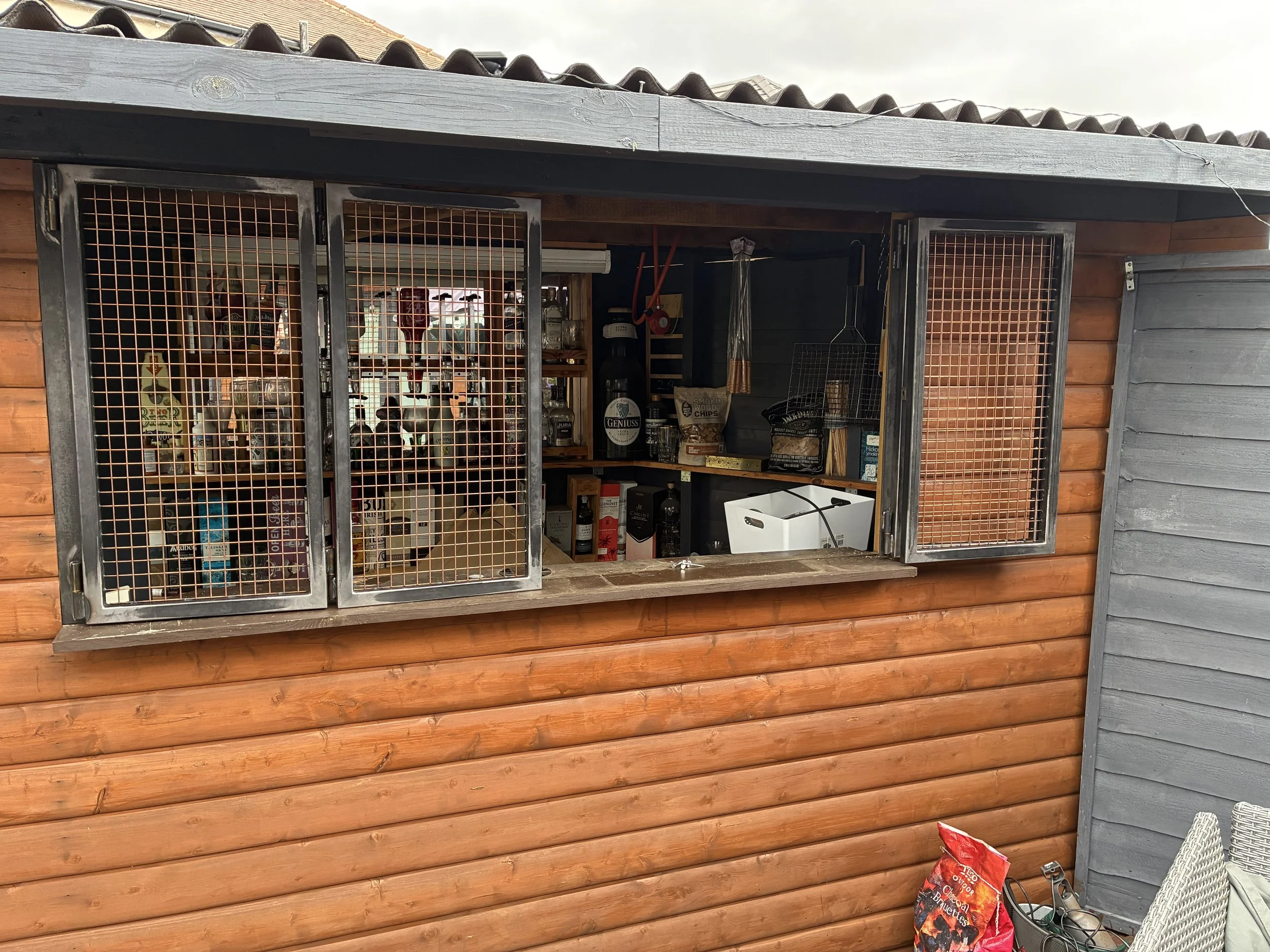 Bespoke bifolding steel bar shutters with mesh panels, combining an industrial look with a secure, lockable design that looks the part open or closed.