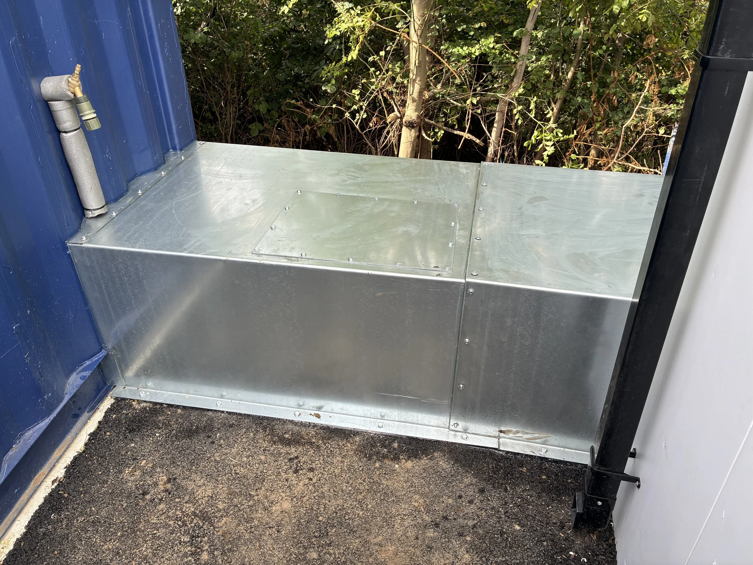 Galvanised sheet utility cover, installed and sealed for weatherproofing.