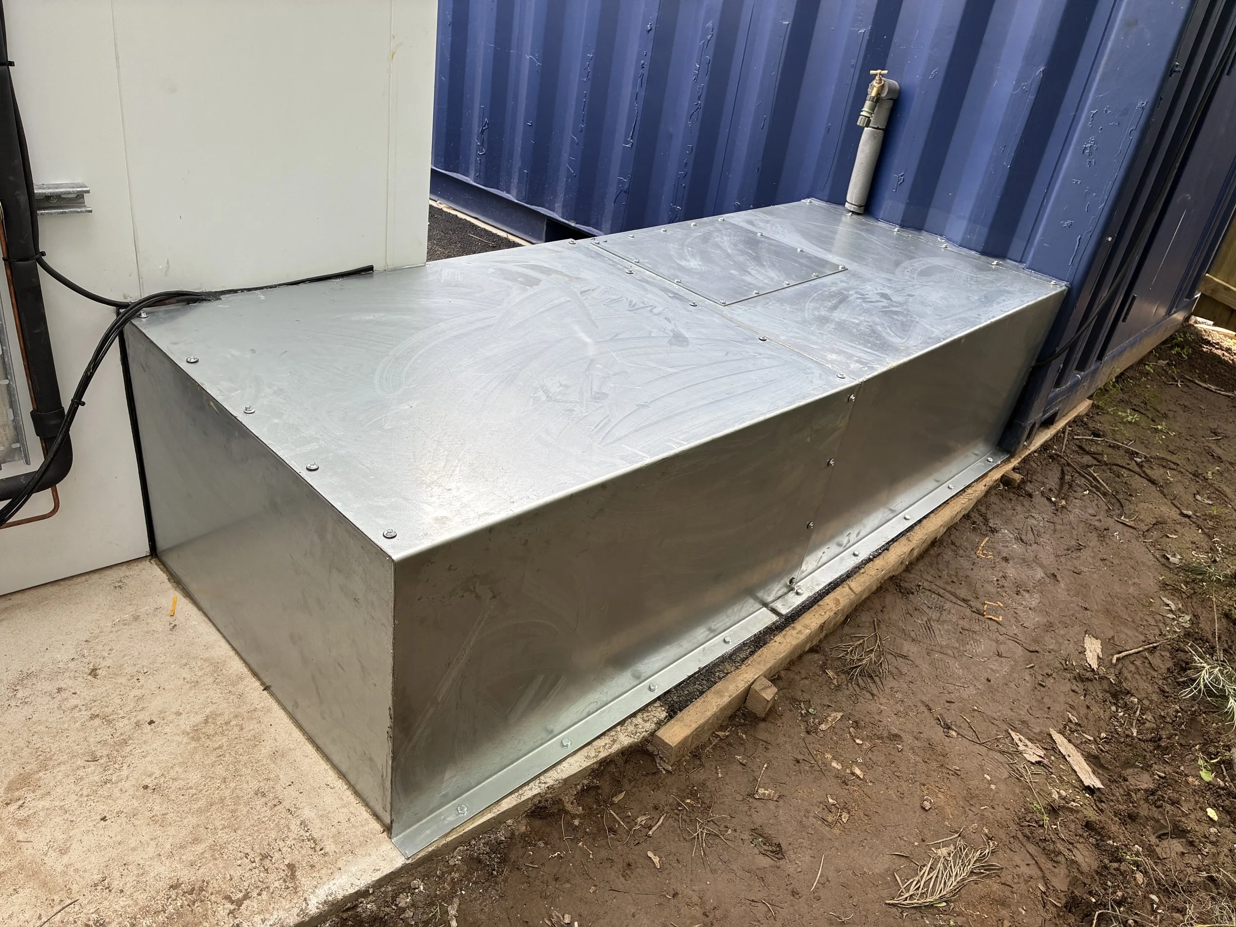 Galvanised sheet utility cover, installed and sealed for weatherproofing.