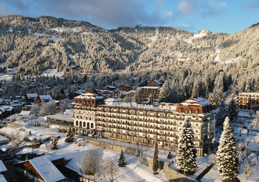 A large hotel named Vila's Palace in a snowy mountain town surrounded by snow-covered trees and buildings.
