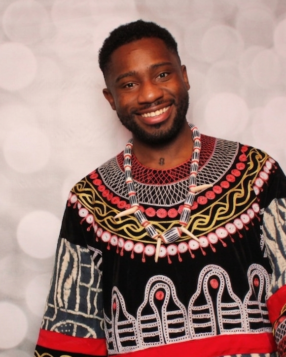 Mallet Y. Njonkem smiling in a black, red, and white patterned top.