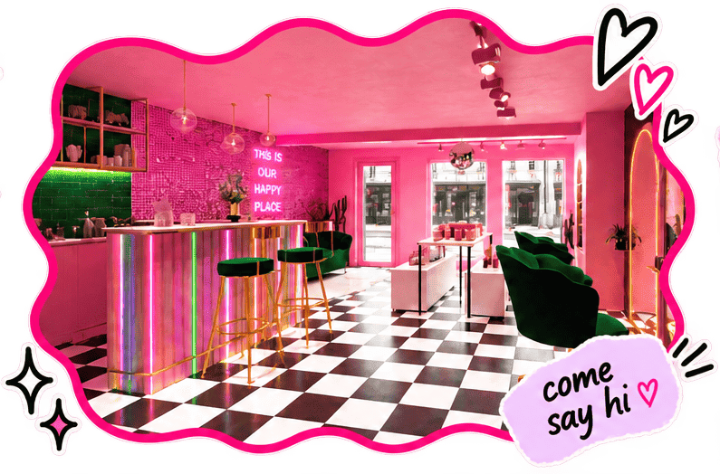 A brightly lit, pink-themed cafe with checkerboard black and white floor, neon signs, green velvet chairs, and a colorful, illuminated bar counter.