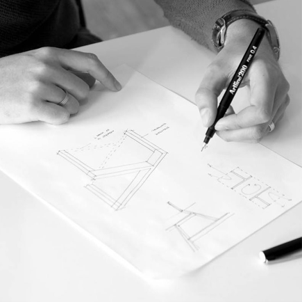 Persoon die technische tekeningen maakt op papier met pen.