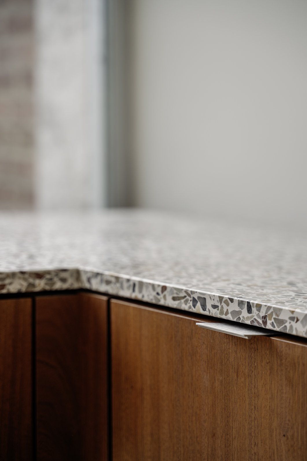 Close-up van een keukenkast met een terrazzo werkblad en houten fronten.