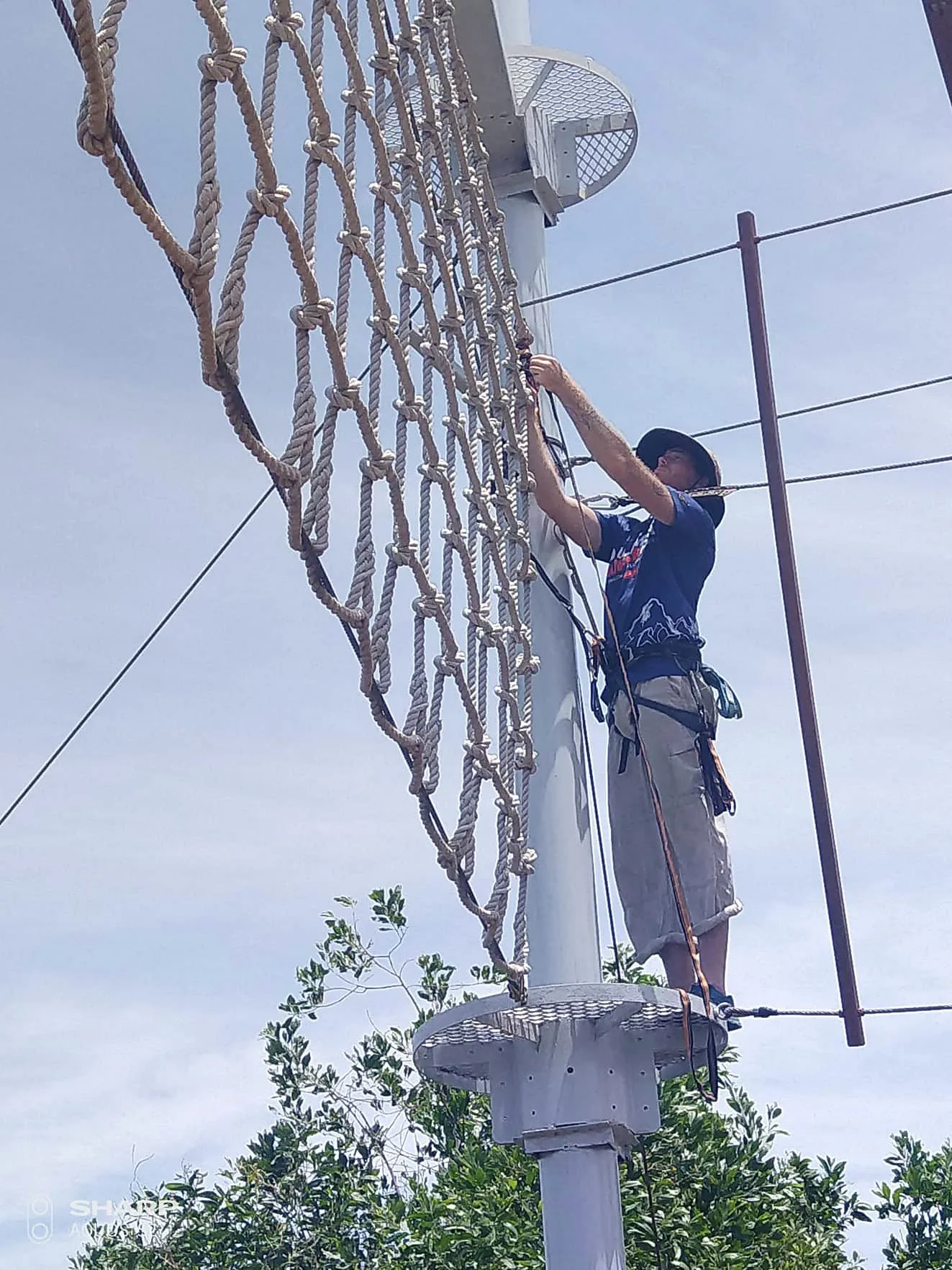 Technical crew inspecting and adjusting elements of a high rope challenge course.