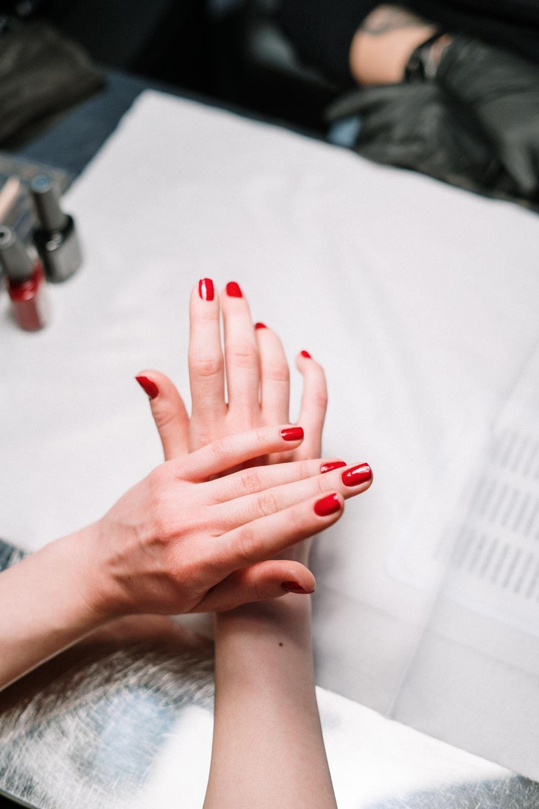 Hände mit rot lackierten Fingernägeln nach einer Maniküre