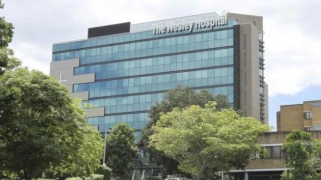 A modern glass hospital building with trees in the foreground and the sign 'The Western Hospital' visible at the top.