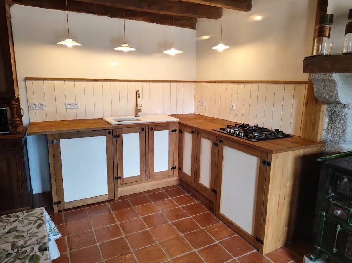 Kitchen with wooden cabinets, white paneling, a sink, and a stove, tile floor, under a sloped ceiling with hanging lights.