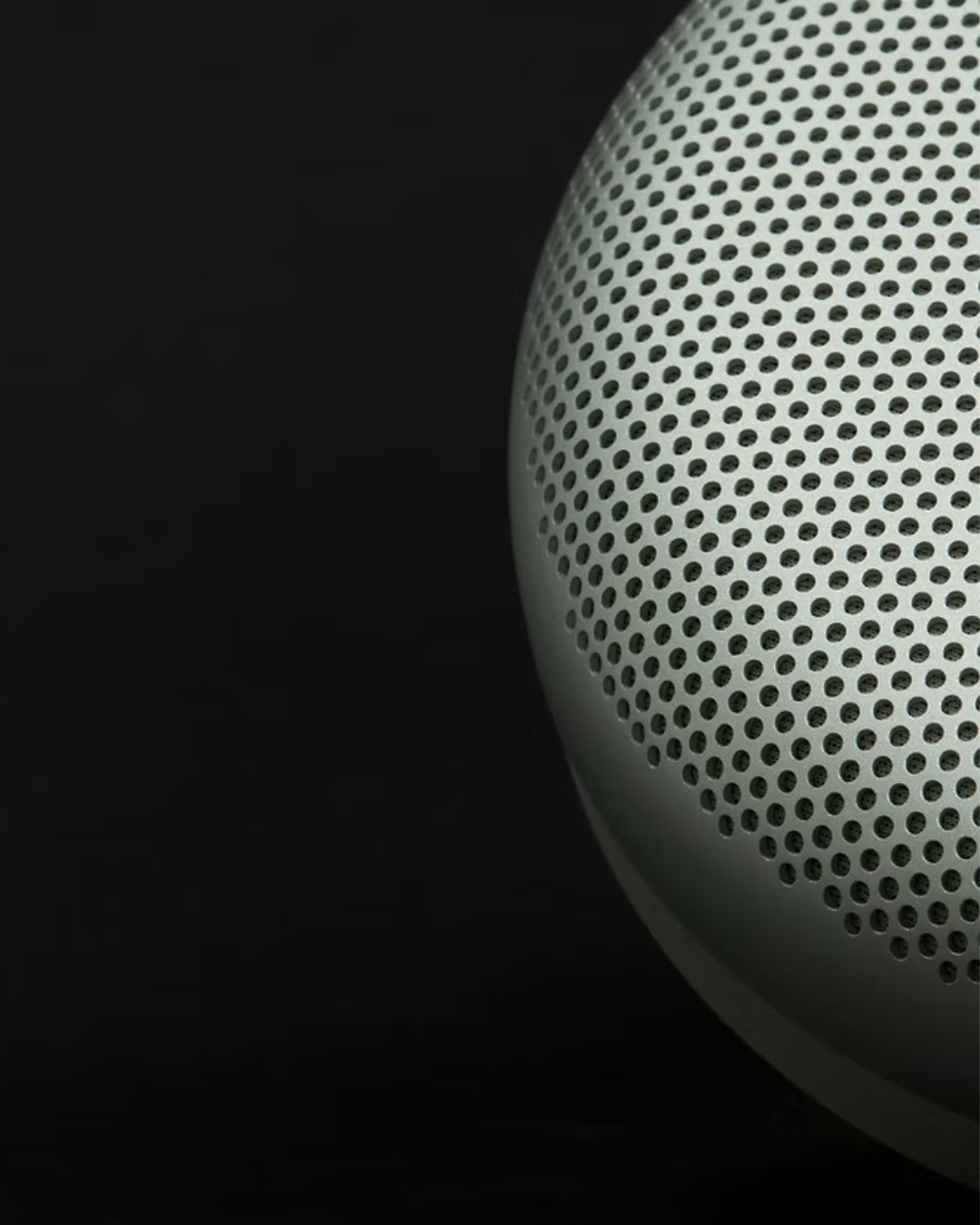Close-up of a white, perforated speaker grille on a black background.