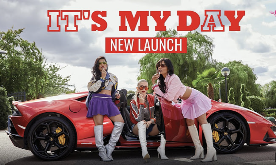 Three fashionable women posing with a red sports car outdoors under a cloudy sky and trees.
