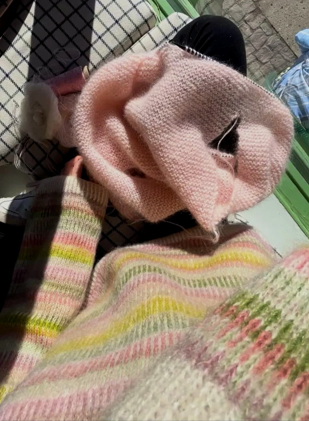 Bunter Fair-Isle-Pullover in Grün- und Rosatönen gestrickt aus Mohair getragen von einer Frau mit rosanem Mohair Strickpullover auf den Beinen liegend