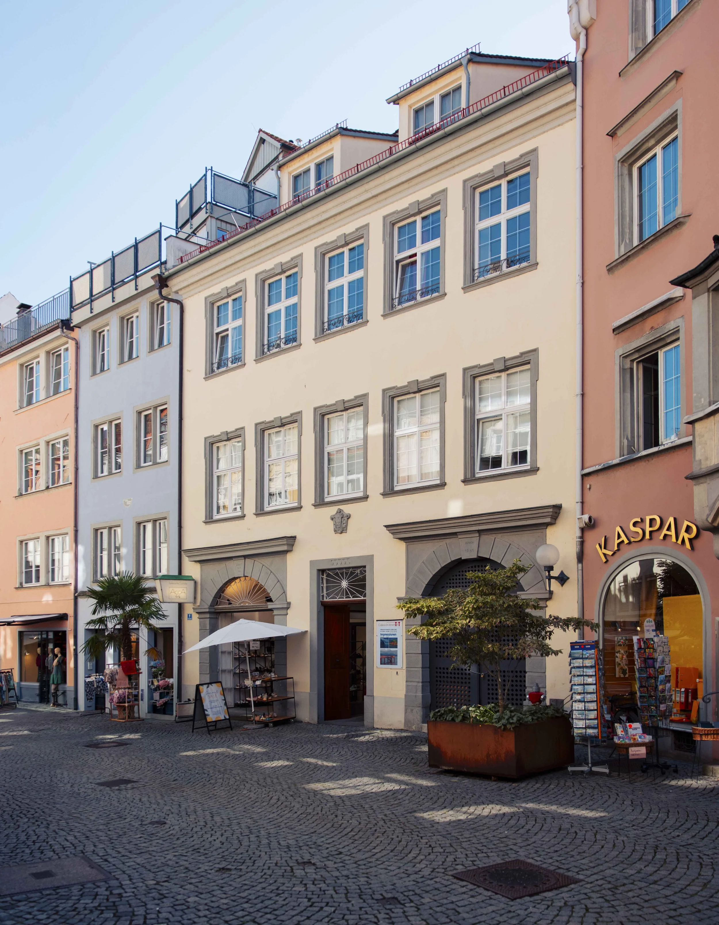 Bunte historische Gebäude an einer belebten, gepflasterten Fußgängerzone in Deutschland mit kleinen Geschäften, Ständen und Sitzgelegenheiten im Freien.