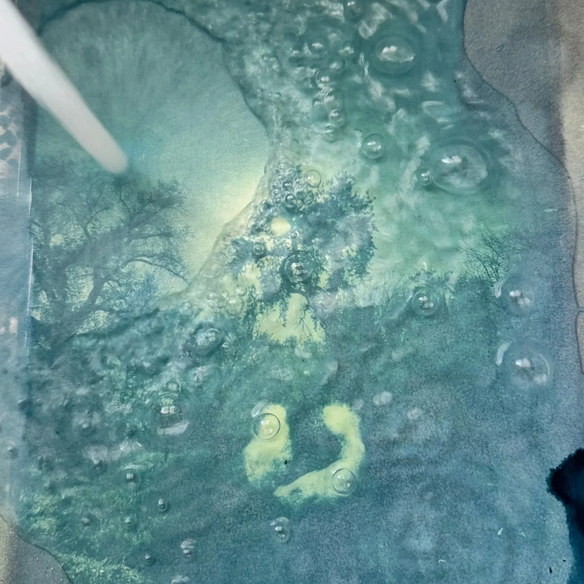 Close-up of water bubbling and splashing as it flows over a surface, possibly a hot tub or fountain, with visible ripples and reflections of trees.