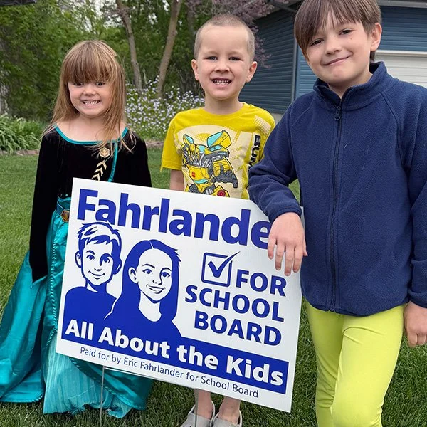 three kids holding yard sign