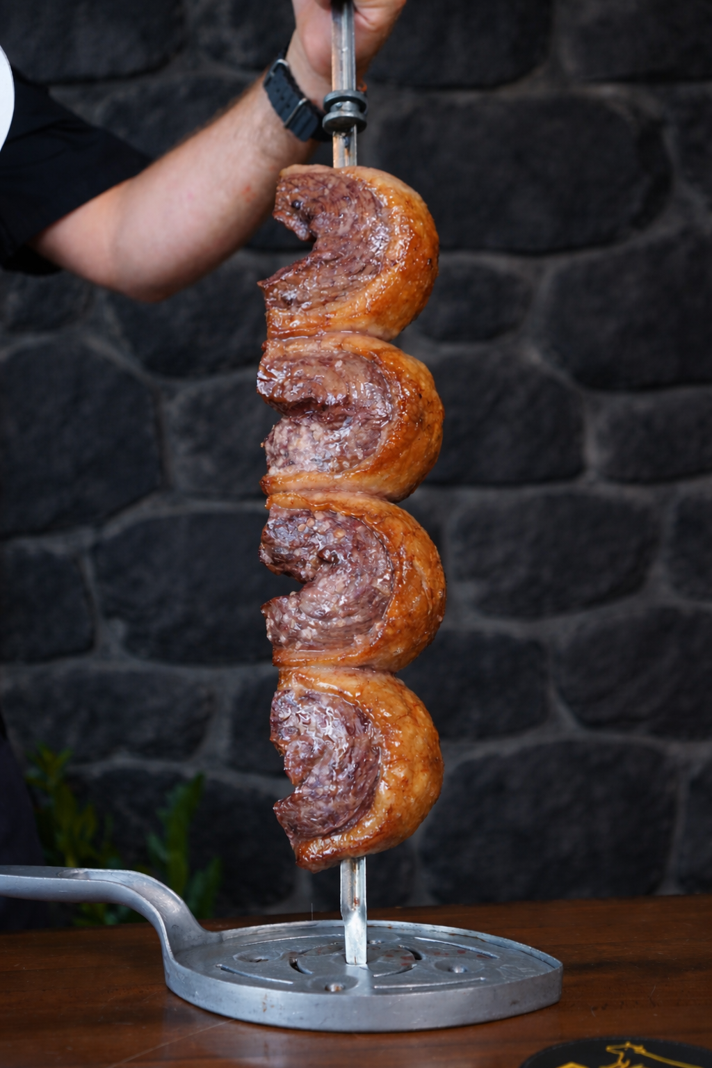 Skewered picanha against dark stone wall.png