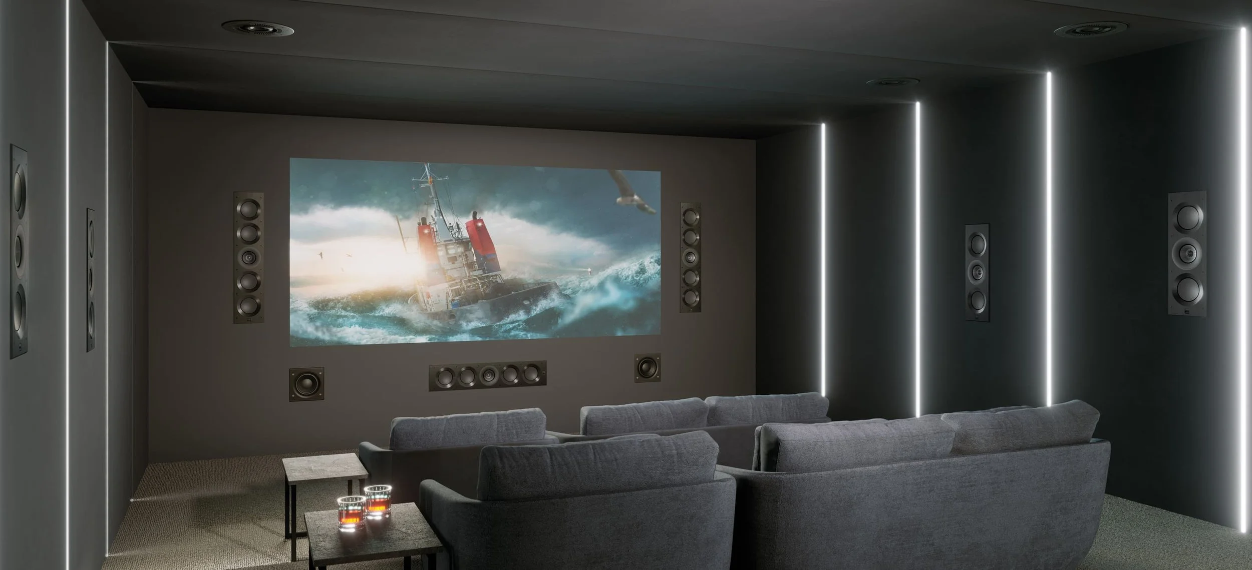 Sala de cine moderna con pantallas de audio envolvente y proyector, mostrando una escena de un barco en medio de olas turbulentas.