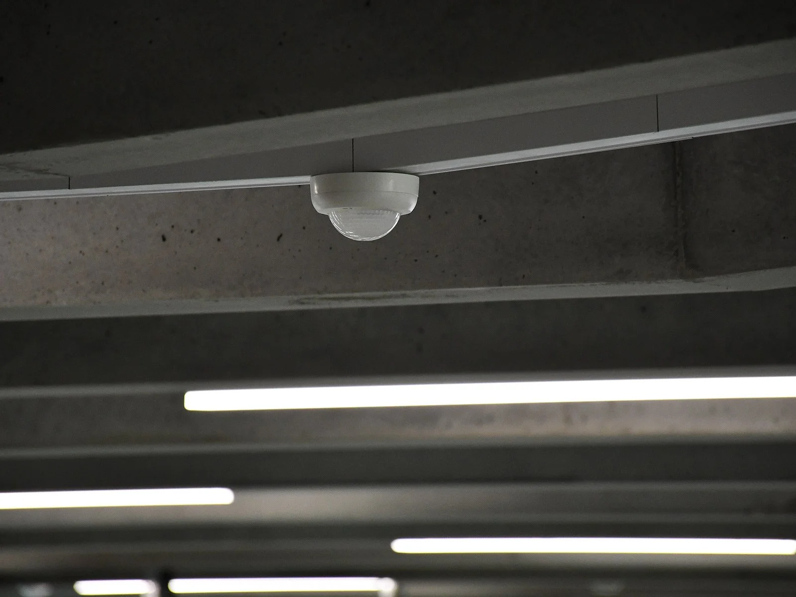 Lámpara LED y sensor de movimiento en un techo de concreto.