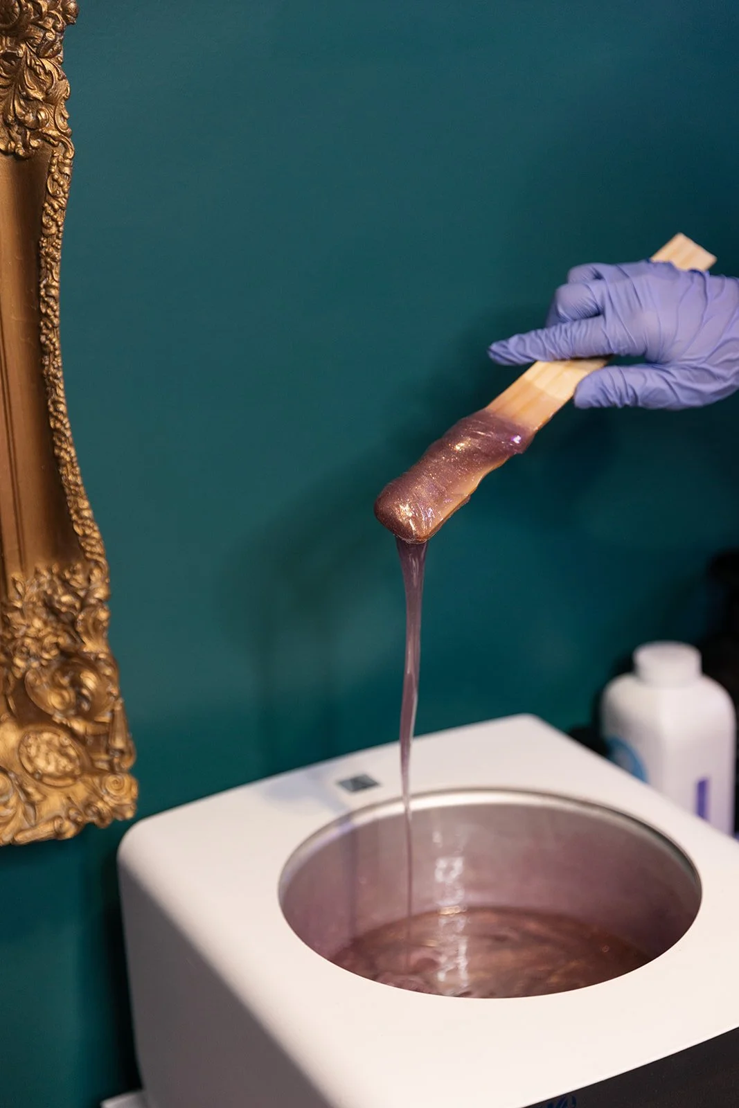 Warm purple hard wax on applicator stick at a professional waxing studio