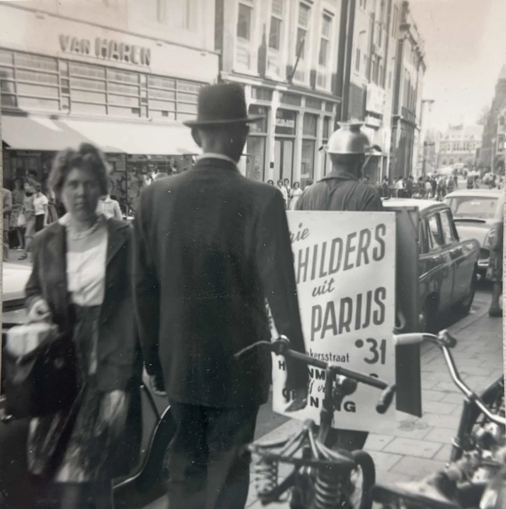Black-and-white photograph of Hans Zandvoort walking through Dordrecht wearing sandwich-board advertising panels and a Sputnik-like headpiece made from a colander and projecting forks, 16 September 1961.