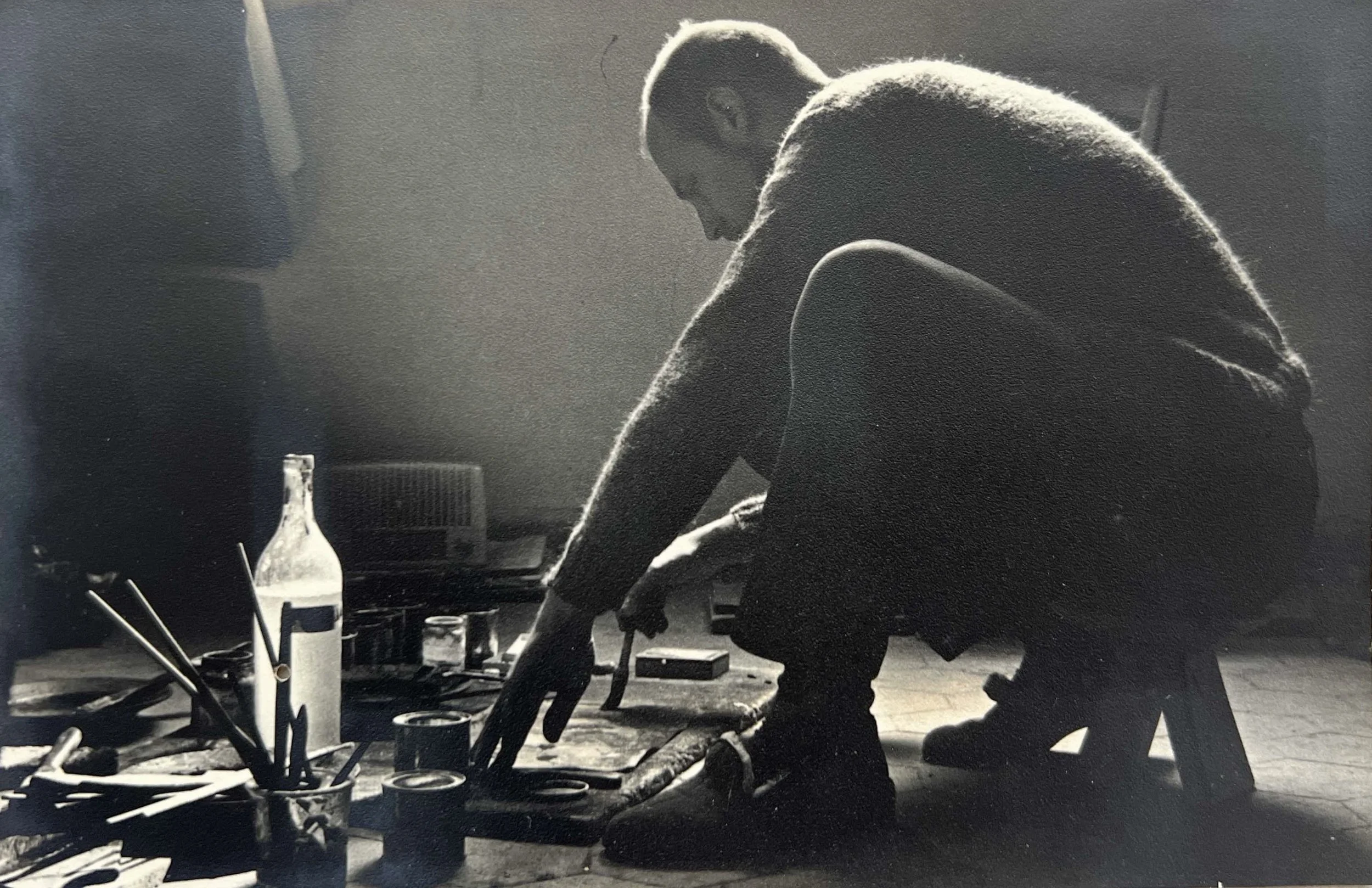 Photograph by Sara Facio of Hans Zandvoort working on the floor with art materials and tools, 1961.