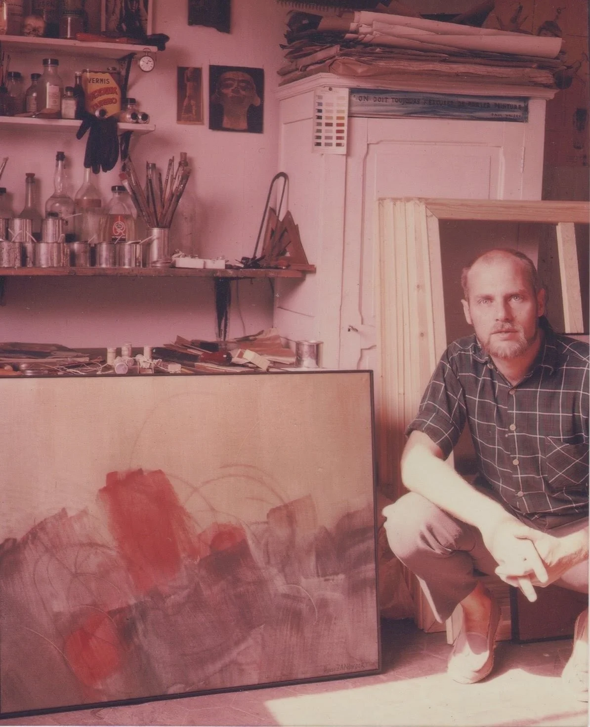 Hans Zandvoort seated in his Rochester, NY studio surrounded by paintings and art materials.