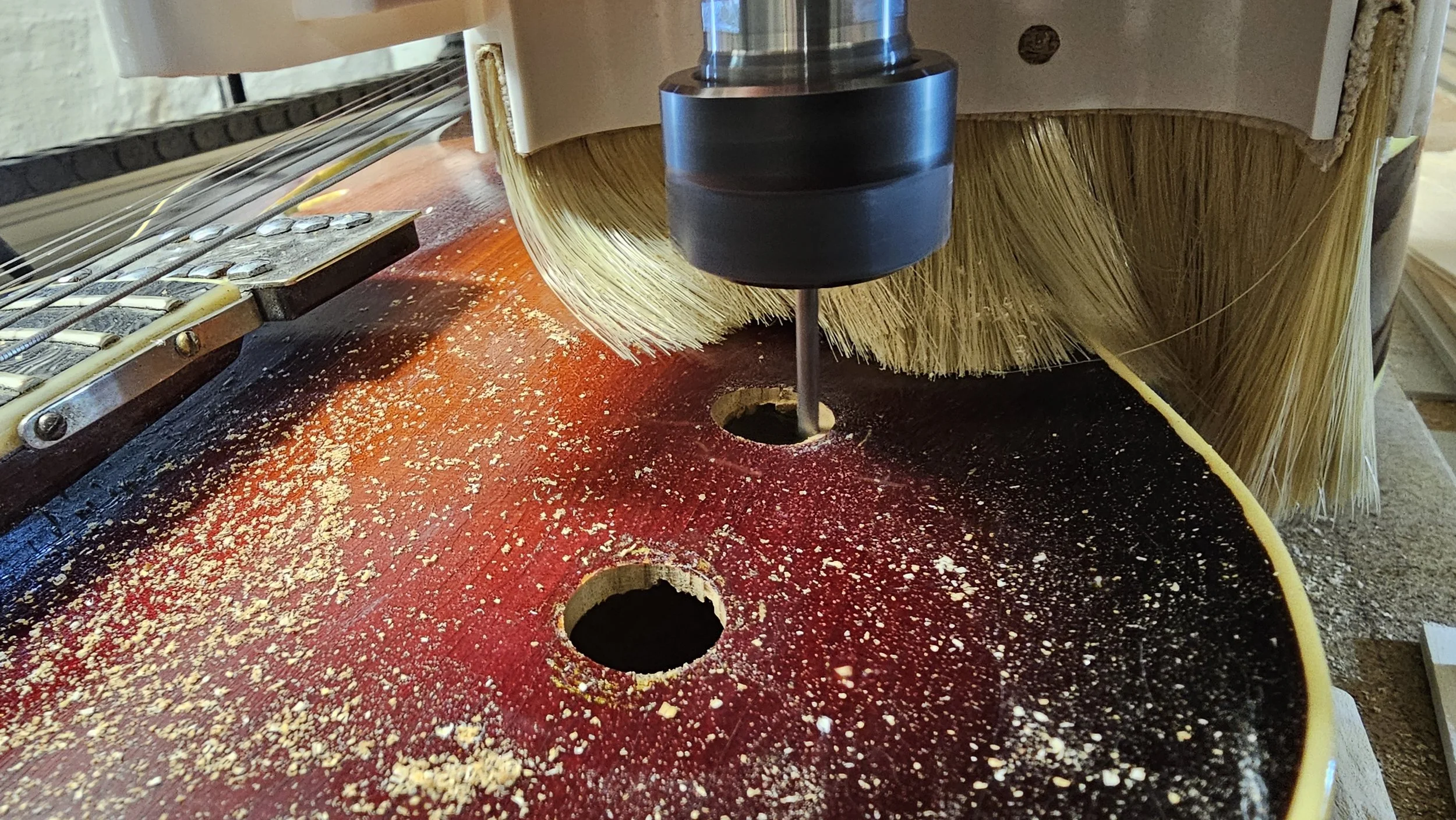 Close-up of a woodworking machine shaping a large piece of wood with a rotary cutter, surrounded by sawdust.