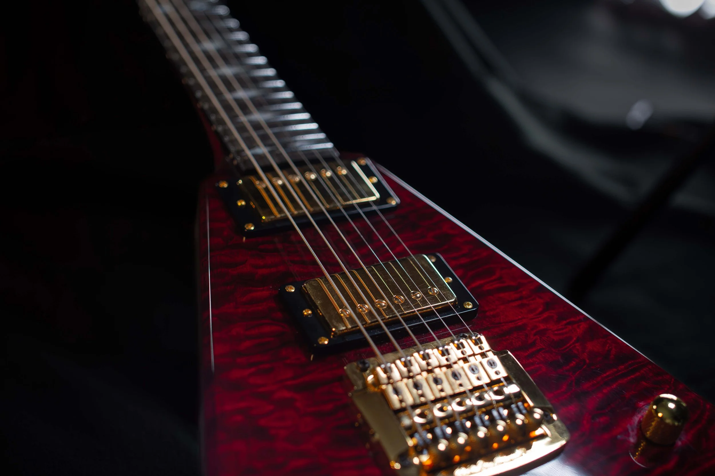 Close-up of a red electric guitar with gold hardware, focusing on the strings and pickups.