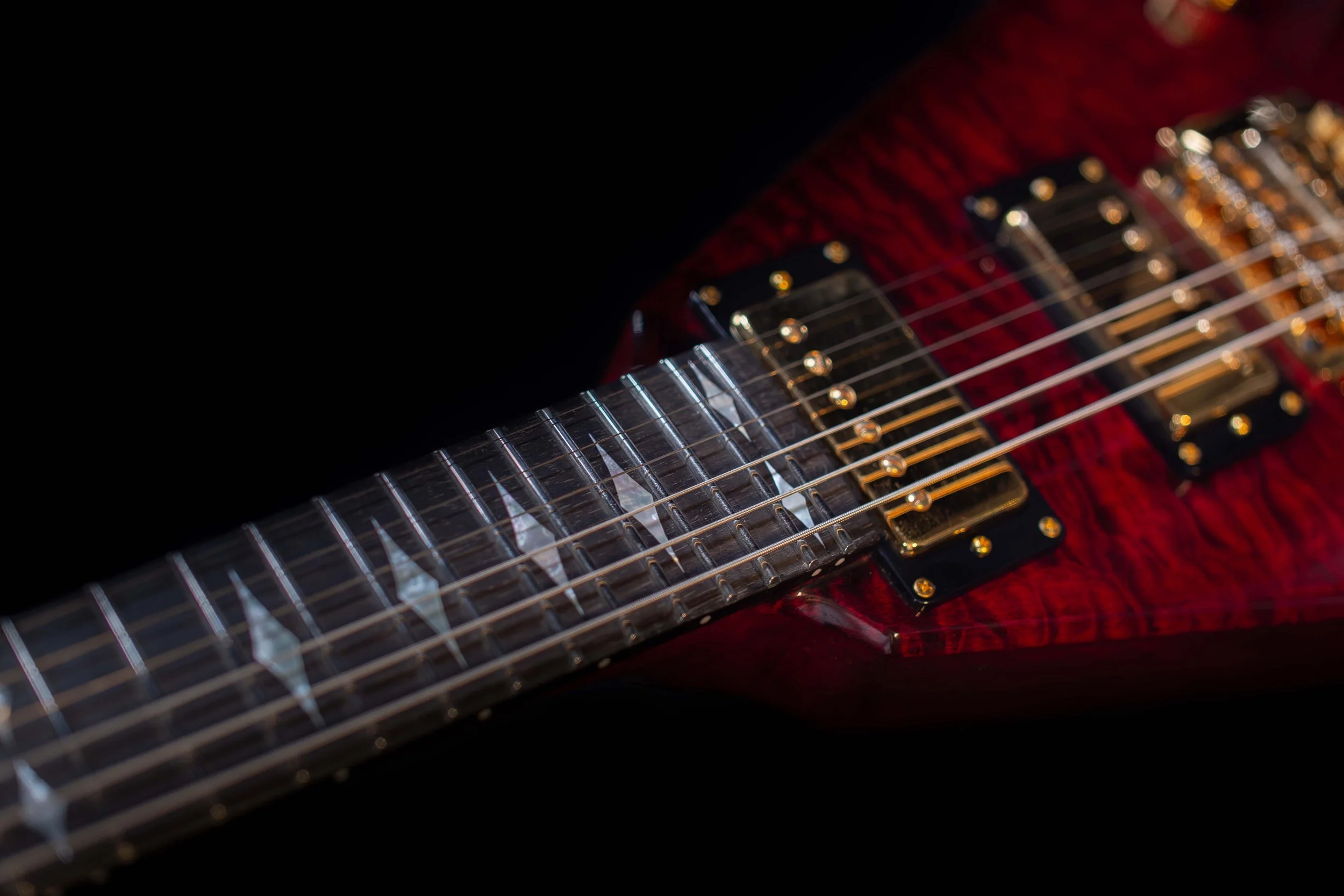 Close-up of a red electric guitar with black pickups and metallic strings.