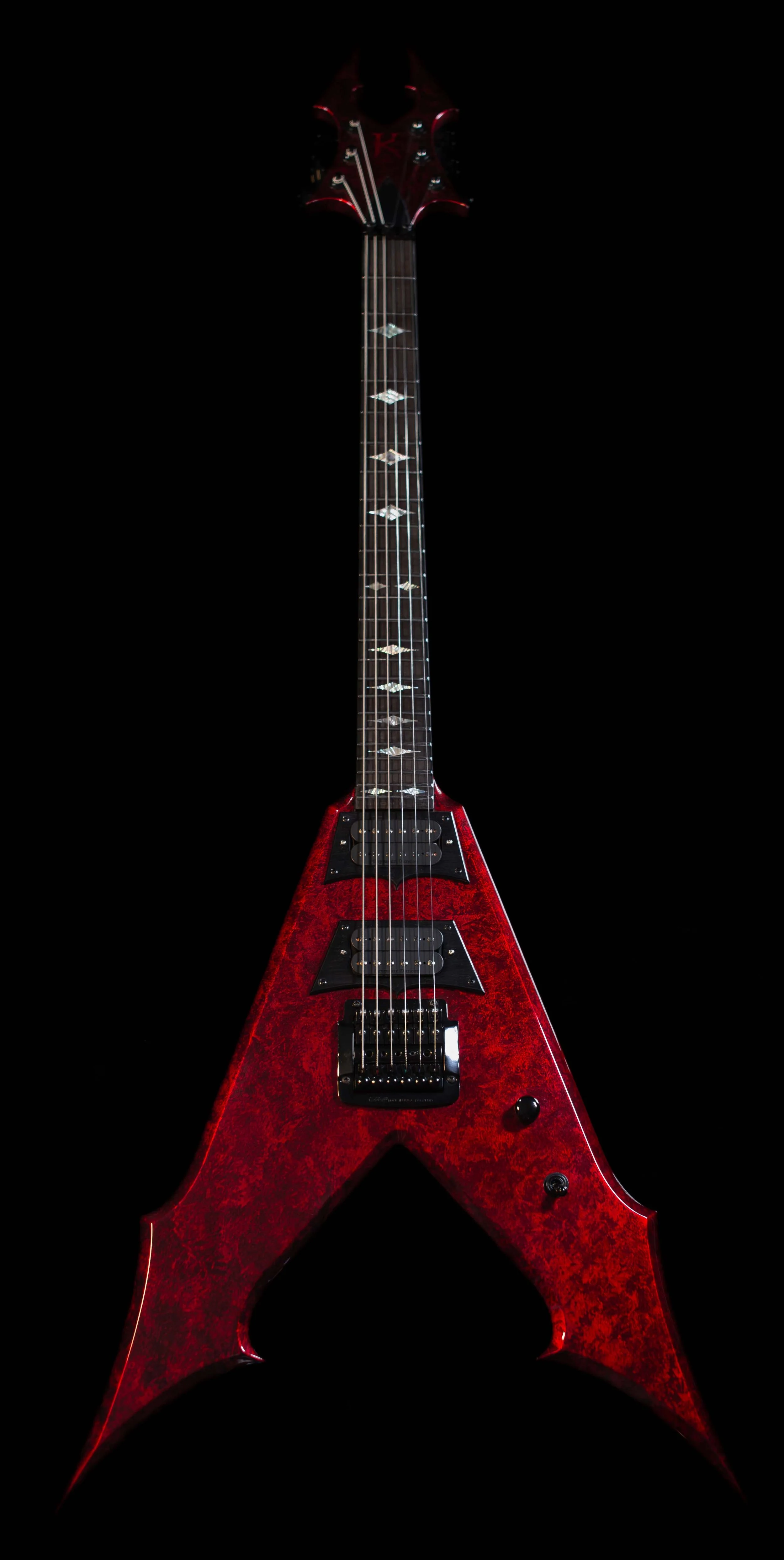 Red electric guitar with a unique V-shaped body and black hardware, displayed against a black background.