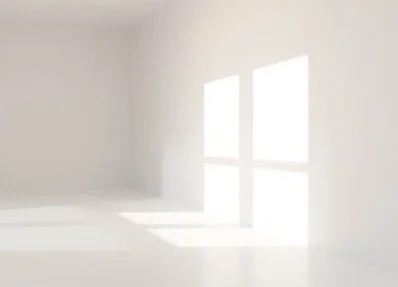 Empty white room with two large windows allowing bright sunlight to shine in.