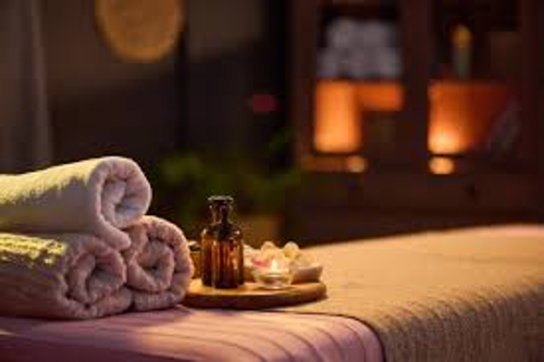 Serviette de bain roulée, huile essentielle et bougie sur une table de spa, ambiance relaxante