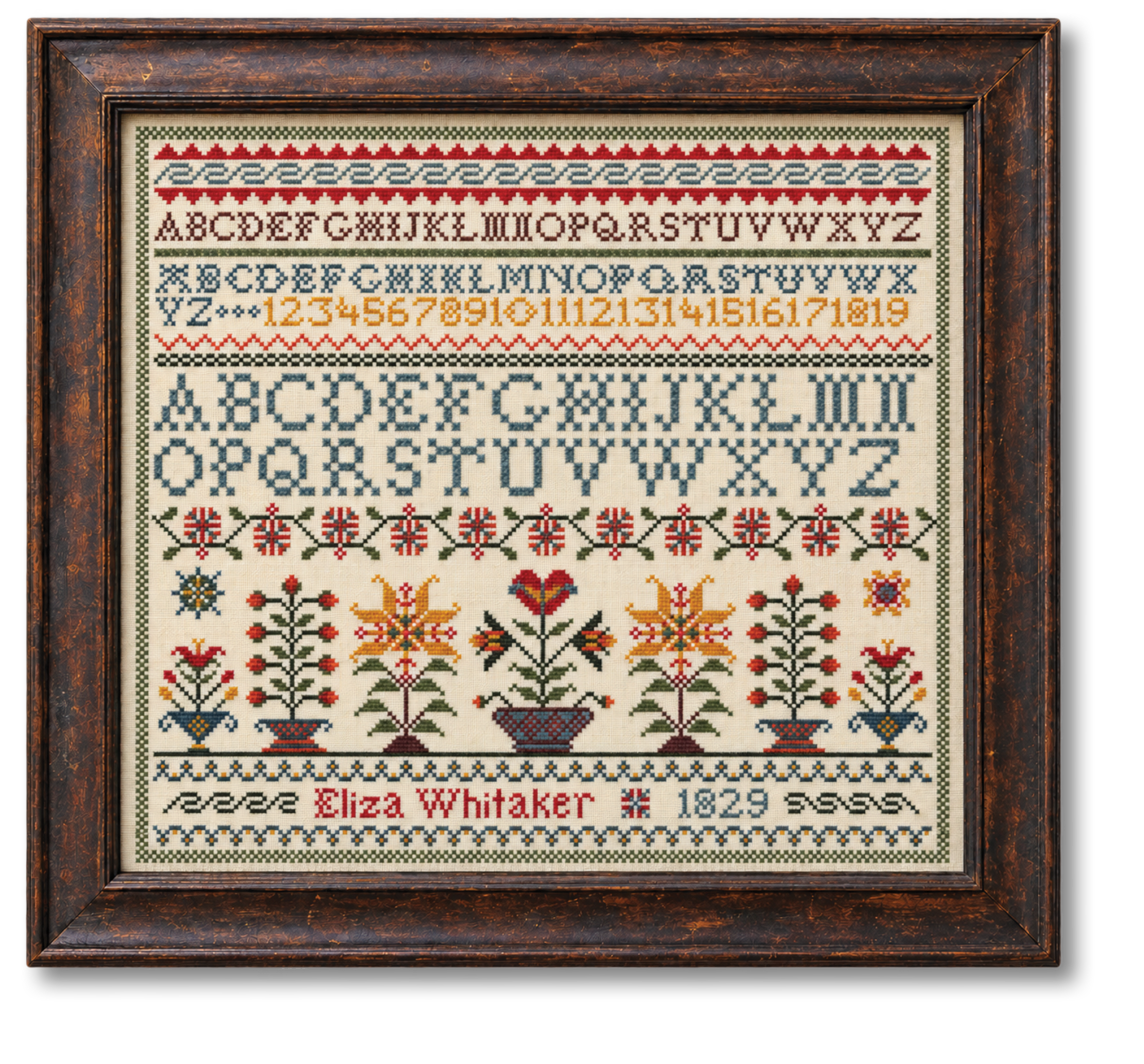 Cross-stitch sampler in a wooden frame with alphabet, numbers, and floral patterns.