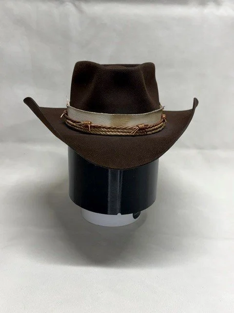A cowboy hat decorated with a band, displayed on a black and white cylindrical stand.
