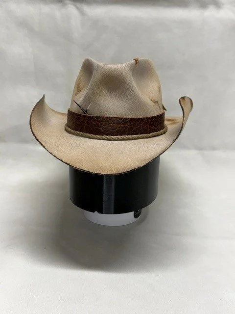 A beige cowboy hat with a brown band on display against a plain background.