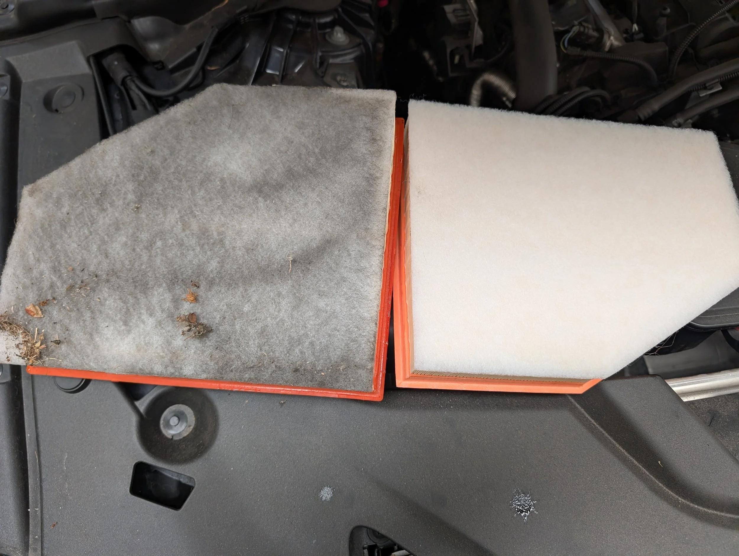 Comparison of two automotive air filters, one dirty and one clean, on a black surface