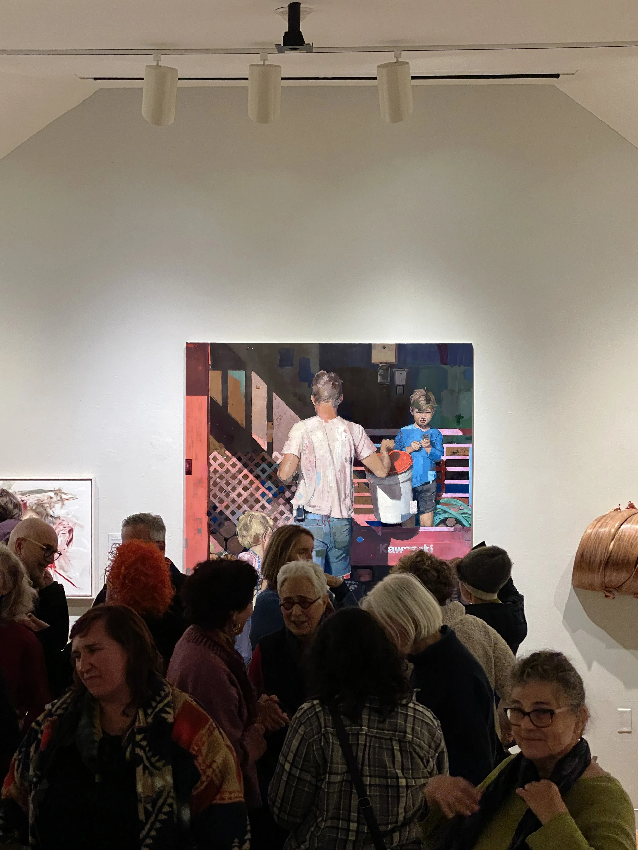 Visitors gather in a gallery in front of a painting of an adult holding a bucket and two children beside a utility vehicle.
