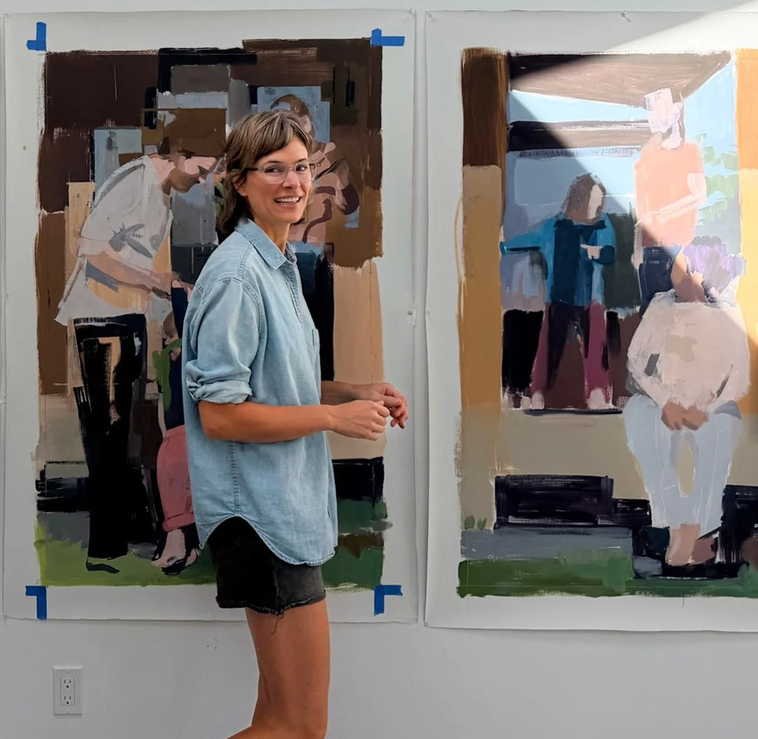 Caitlin Winner smiling in her studio in front of her large narrative paintings.