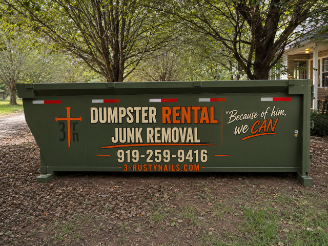 Green dumpster with lettering advertising Dumpster Rental and Junk Removal, phone number 919-259-9416, website 3-rustynails.com, with a tree and residential house in the background.