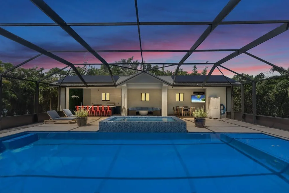 The screened pool and covered lanai at The Zen House at dusk, under a pink sunset.