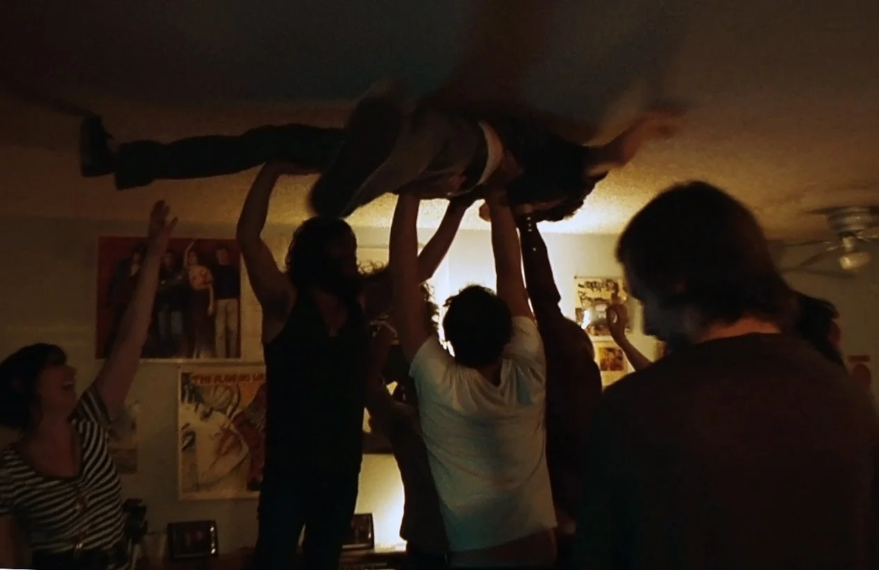 Breaking: Los Angeles documentary still of Vanaprasta band and friends lifting a partygoer during a party.