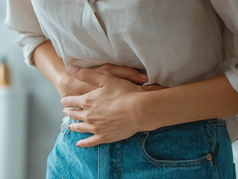 Person holding their stomach, possibly experiencing pain or discomfort.