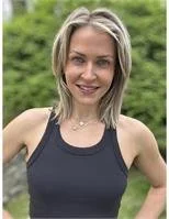 A woman with shoulder-length blonde hair, smiling, outdoors in a sleeveless black top.